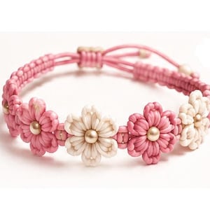 Könnte beinhalten: Ein Makramee-Armband mit abwechselnd rosa und weißen Kordelblüten. Jede Blüte hat in der Mitte eine kleine, runde, goldfarbene Metallperle. Das Armband besteht aus einem geflochtenen rosa Kordelband und verfügt über einen verstellbaren Schiebeknoten.