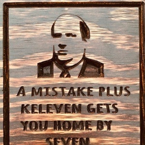 Puede incluir: Un letrero de madera con un acabado de madera quemada presenta una silueta de un hombre con el texto "A mistake plus eleven gets you home by seven. - Kevin Malone".