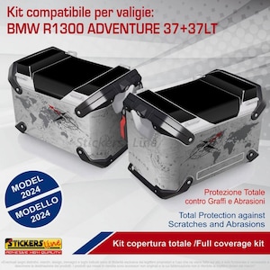 Könnte beinhalten: Zwei Motorradkoffer mit Kartenmuster und schwarzen Oberteilen. Die Koffer sind mit "BMW R1300 ADVENTURE 37+37LT" beschriftet und tragen den Text "Total Protection against Scratches and Abrasions."