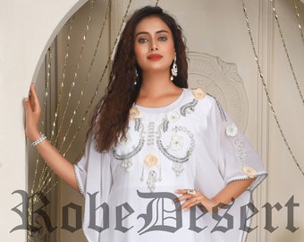 May include: A white kaftan with a beaded and embroidered design. The kaftan has a long, flowing silhouette and is perfect for a special occasion.