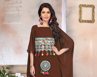 May include: A brown maxi dress with colorful embroidered geometric patterns and pom-poms. The dress has a loose, flowing silhouette and a round neckline.