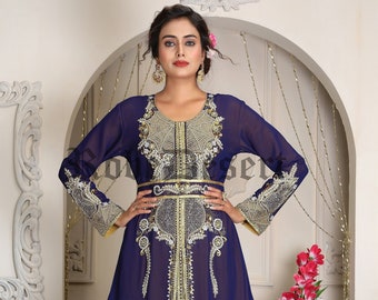 May include: A long, flowing blue kaftan with gold and silver embroidery. The kaftan has a yellow sash and a deep V-neckline. The sleeves are long and flowing. The kaftan is decorated with a traditional design.