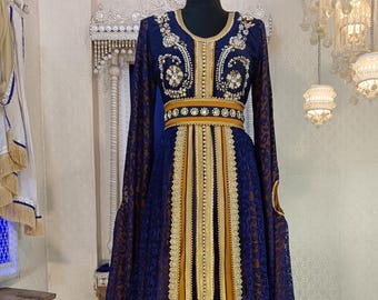 May include: A long, blue and gold kaftan with intricate embroidery and beading. The kaftan has a long, flowing skirt and long sleeves. The fabric is sheer and delicate.