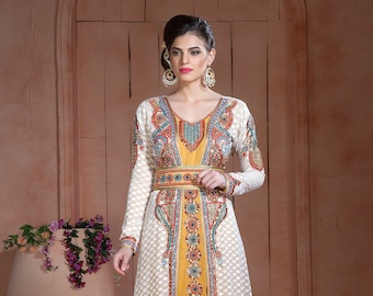 May include: A white and yellow long-sleeved dress with intricate embroidery and beading. The dress has a V-neckline and a long, flowing skirt.