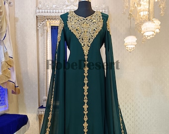 May include: A long, dark green dress with gold embroidery and embellishments. The dress has a V-neckline and long sleeves. The sleeves are wide and flowy. The dress is floor-length and has a flowing skirt.