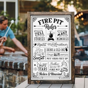 May include: A black and white sign with the text "Fire Pit Rules" and a list of rules for enjoying a fire pit, including telling stories, making memories, roasting marshmallows, having a drink, watching the sunset, putting your feet up, counting stars, gathering around the fire pit, and relaxing and unwinding.