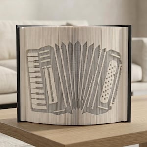Op de afbeelding: Een decoratieve boeksculptuur met een accordeonontwerp. De accordeon is gemaakt door de pagina's van een boek zorgvuldig te snijden en te vouwen. De sculptuur wordt gepresenteerd op een houten oppervlak met een neutrale achtergrond.