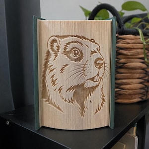 Peut inclure: Une sculpture de livre présentant un design d'art en pages pliées représentant une tête de marmotte. Les pages sont déployées pour créer un portrait en trois dimensions de l'animal, montrant ses yeux, son nez, ses moustaches et ses dents.