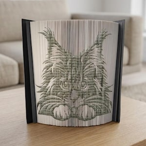 Könnte beinhalten: Dekorative Buchskulptur mit einem detaillierten Katzengesicht. Das Kunstwerk wird durch Falten der Buchseiten erstellt, mit einem schwarzen Rahmen auf jeder Seite. Das Katzengesicht ist in Grau- und Beigetönen gehalten, mit Text von den Buchseiten.