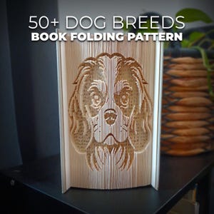 Op de afbeelding: Een boekvouwpatroon met een hondengezicht. De tekst "50+ DOG BREEDS BOOK FOLDING PATTERN" staat bovenaan. Het gezicht van de hond is vakkundig uit de pagina's gesneden, wat de kunst van het boekvouwen laat zien.