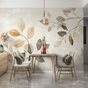 May include: A dining room scene featuring a wooden table and chairs, with a decorative wall mural of stylized leaves in shades of brown and beige. The room is decorated with vases and pillows, creating a warm and inviting atmosphere.