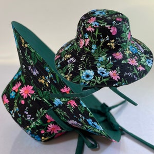 May include: Two black and green floral print bucket hats with green ties. The hats are made of fabric and have a wide brim.