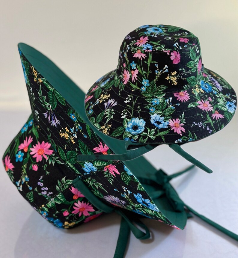 May include: Two black and green floral print bucket hats with green ties. The hats are made of fabric and have a wide brim.