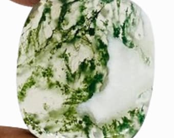 May include: A polished, square-cut gemstone with a unique pattern. The stone features a mix of white and green hues, with the green resembling moss or plant-like inclusions. The overall shape is rounded, and the surface is smooth and reflective.