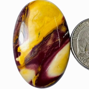 Puede incluir: Una piedra pulida lisa de forma ovalada con patrones de color amarillo, blanco y burdeos.