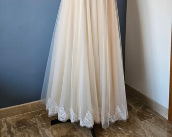 Op de afbeelding: Een witte strapless kanten korset met een tule rok. De rok heeft een witte kanten zoom.