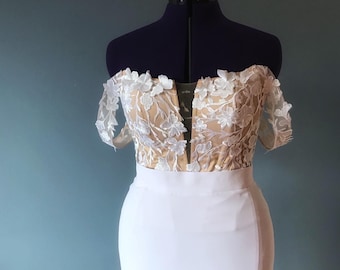 May include: A white off-the-shoulder wedding dress with a lace bodice and a fitted skirt.