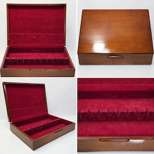 Può includere: Un cofanetto rettangolare in legno con finitura marrone lucida e coperchio incernierato. L'interno è rivestito in velluto rosso intenso e presenta un inserto scanalato progettato per mantenere diversi oggetti in ordine.