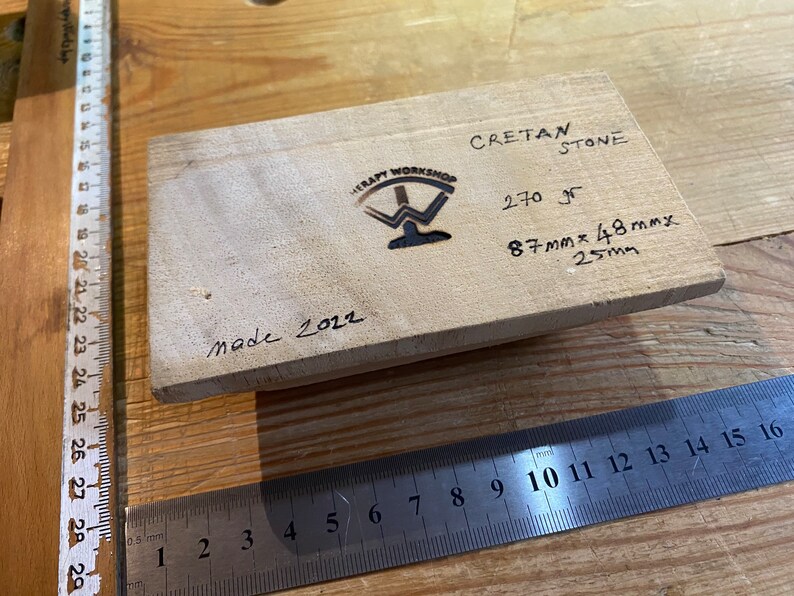 Peut inclure: Un bloc de bois avec le texte "Cretan Stone" et "270 gr" &eacute;crit dessus. Le bloc a &eacute;galement les dimensions "87mmx48mmx25mm" &eacute;crites dessus. Le bloc est marqu&eacute; "Made 2022" et porte le logo de "Therapy Workshop".