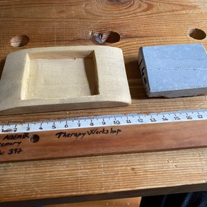 May include: A wooden tray with a rectangular cutout and a gray stone block. The tray is 10 inches long and the stone block is 3 inches wide. The ruler is labeled "Therapy Workshop" and "SAVAŞ ALDEMIR 1978 Memory 5A; No: 397".