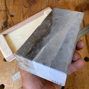 Puede incluir: Una piedra de afilar rectangular gris y marr&oacute;n con una etiqueta blanca en la parte inferior que dice "2024 98".