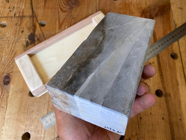 Puede incluir: Una piedra de afilar rectangular gris y marr&oacute;n con una etiqueta blanca en la parte inferior que dice "2024 98".