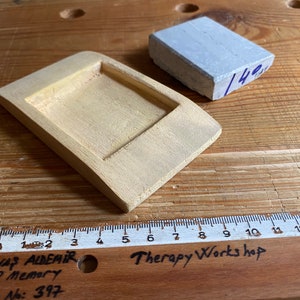 May include: A light yellow wooden tray with a rectangular recess, a gray rectangular block, and a wooden ruler with the text "Therapy Works hop" and "SAVAŞ ALDEMİR 1978 Memory SA: No: 397".