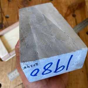 Puede incluir: Una piedra de afilar rectangular gris con el n&uacute;mero azul "0881" escrito en la parte inferior. La piedra tiene una superficie rugosa y texturizada.