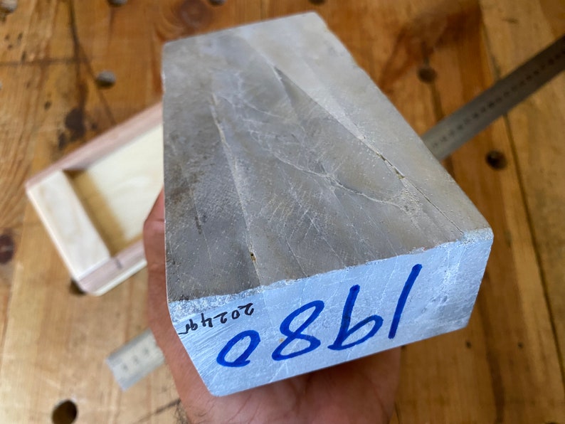 Puede incluir: Una piedra de afilar rectangular gris con el n&uacute;mero azul "0881" escrito en la parte inferior. La piedra tiene una superficie rugosa y texturizada.