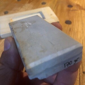 May include: A grey rectangular sharpening stone with a white edge and the number "170 gr" written on the side.