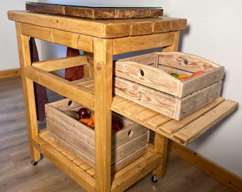May include: A light brown wooden kitchen cart on wheels featuring a thick top surface, a lower shelf, and a side extension. Two light-colored wooden crates are placed on the shelves, containing various fresh vegetables and fruits.