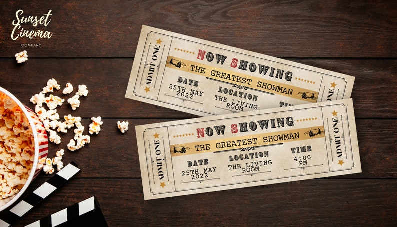 Peut inclure: Deux billets de cin&eacute;ma de style vintage avec le texte "Now Showing The Greatest Showman" sur une surface en bois brun. Les billets ont une date du 25 mai 2022, un lieu "The Living Room" et une heure de 16h00.