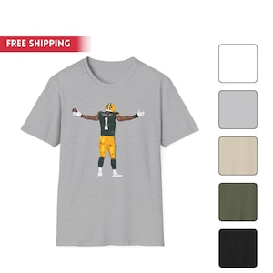 May include: A light gray t-shirt featuring a football player in a green and yellow uniform with the number 1. The player is holding a football and has his arms outstretched. The text "FREE SHIPPING" is in a red banner.