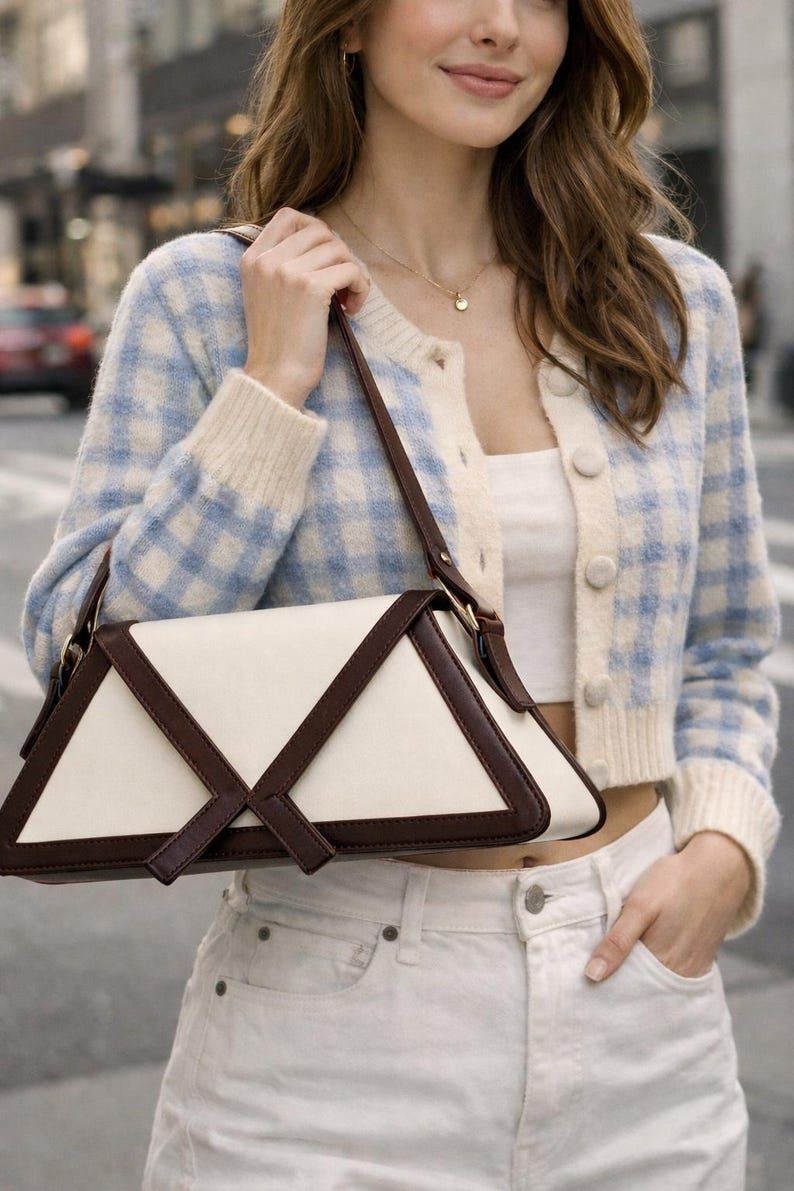 Peut inclure: Un sac &agrave; main cr&egrave;me avec des accents en cuir marron fonc&eacute; et un design g&eacute;om&eacute;trique. Le sac est port&eacute; par une personne portant un cardigan &agrave; carreaux bleu et blanc et un jean blanc.