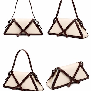 Peut inclure: Un sac &agrave; main cr&egrave;me avec une forme triangulaire unique. Le sac est orn&eacute; de bordures et de sangles marron fonc&eacute; qui se croisent sur le devant. La poign&eacute;e est &eacute;galement marron fonc&eacute;. Le sac est pr&eacute;sent&eacute; sous plusieurs angles.