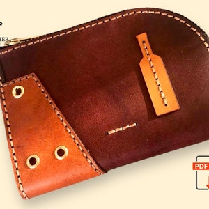 May include: A brown leather wallet with a zip closure and a brown leather flap with three gold eyelets. The wallet has a small brown leather pocket on the front with a stitched design.