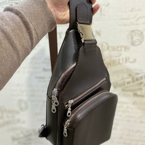Peut inclure: Un sac &agrave; bandouli&egrave;re en cuir marron avec plusieurs compartiments &agrave; fermeture &eacute;clair et une boucle argent&eacute;e.