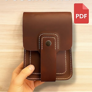 Könnte beinhalten: Eine braune Ledertasche mit weißen Nähten und einem Klappenverschluss. Das Bild enthält den Text "DIY LEATHER POUCH PATTERN" und ein rotes PDF-Symbol. Die Tasche wird von einer Hand gehalten.