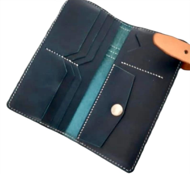 May include: A dark blue leather wallet with a light brown leather strap and a silver button. The wallet has multiple compartments and pockets.