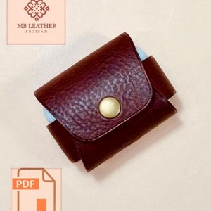 Puede incluir: Una funda de cuero marrón con cierre de botón dorado. La funda está diseñada para guardar objetos pequeños, como auriculares o un llavero. La funda está hecha por MB Leather Artisan.