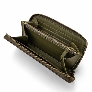 May include: An olive green zip-around wallet with a textured exterior. The interior features a matching olive green lining, multiple card slots, and a central zippered compartment with a metal pull tab, all secured by a brass-toned metal zipper.