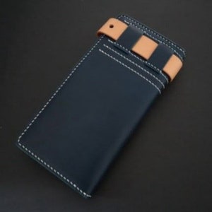 May include: A dark blue leather wallet with a tan leather strap and white stitching. The strap has a decorative pattern of tan leather strips.