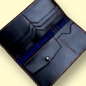 May include: A black leather wallet with a blue interior and orange stitching. The wallet has multiple compartments and a snap closure.