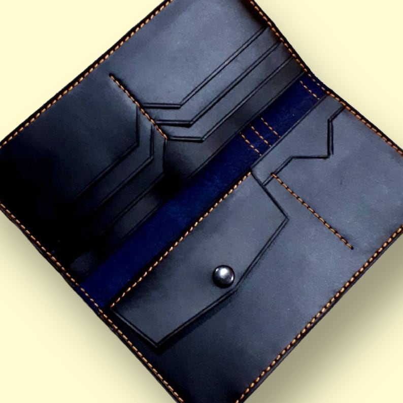 May include: A black leather wallet with a blue interior and orange stitching. The wallet has multiple compartments and a snap closure.