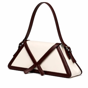 Peut inclure: Sac &agrave; main g&eacute;om&eacute;trique de forme triangulaire. Le corps est de couleur cr&egrave;me, avec des bordures et des accents marron fonc&eacute;. Il poss&egrave;de une poign&eacute;e unique et un motif en forme de croix sur le devant.
