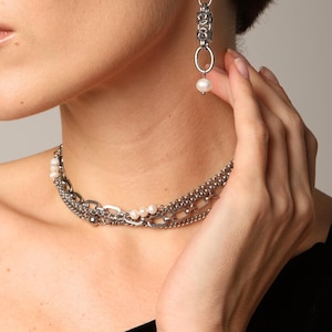 May include: A silver-toned multi-strand chain choker necklace featuring small white pearls interspersed along the links, paired with a matching drop earring consisting of a silver chain link segment and a single white pearl.