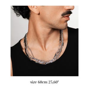 Puede incluir: Un collar de capas en tono plateado que presenta m&uacute;ltiples estilos de cadena, incluyendo una cadena de eslabones gruesos y hebras de cuentas m&aacute;s finas, con una longitud de 60 cm. El collar se lleva al cuello y tiene un acabado met&aacute;lico.