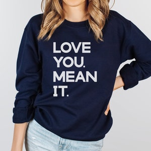 May include: A navy blue sweatshirt with the text "LOVE YOU. MEAN IT." printed in white.