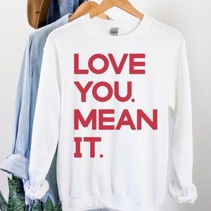 May include: White sweatshirt with red lettering that says "LOVE YOU. MEAN IT."