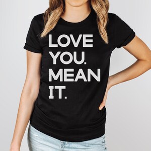 May include: Black t-shirt with white text that reads "LOVE YOU. MEAN IT."